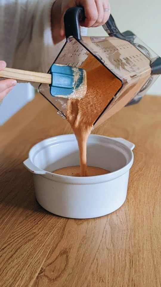 The vegan Buffalo Cashew dip being poured into the baking dish