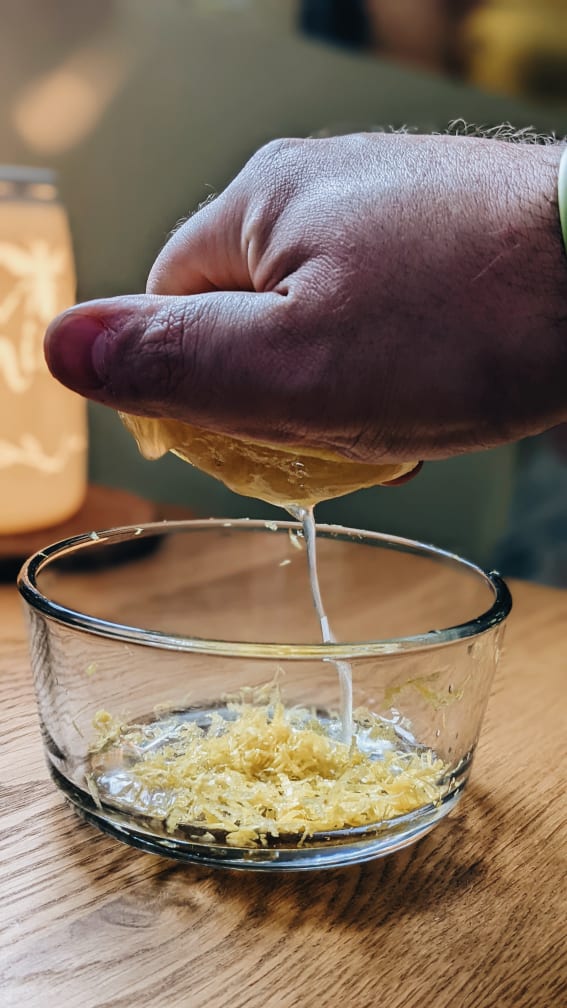 squeezing lemon juice into a bowl of zest